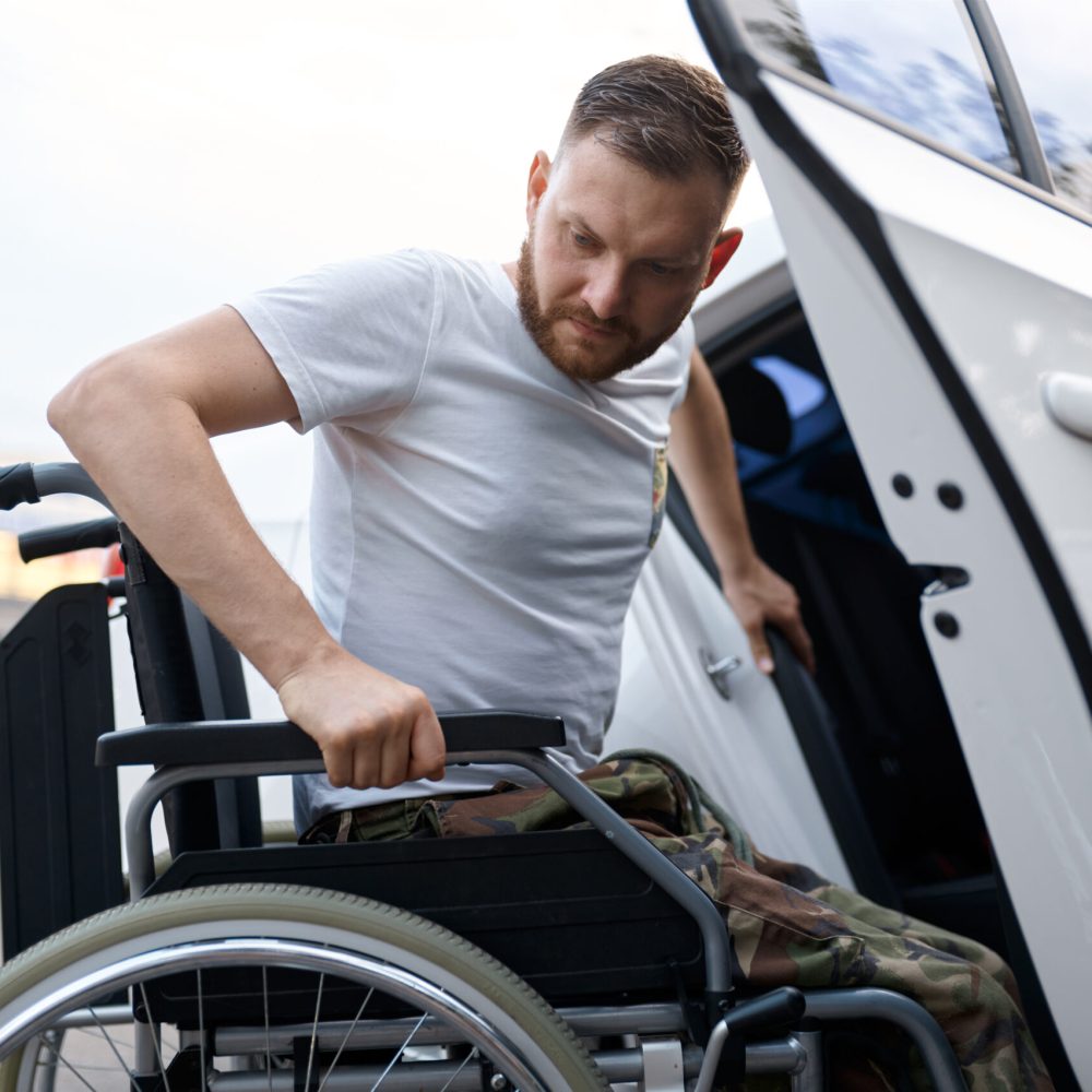 Retired veteran independently transfers from a car to a wheelchair. Paralyzed people and disability, handicap overcoming. Disabled male person